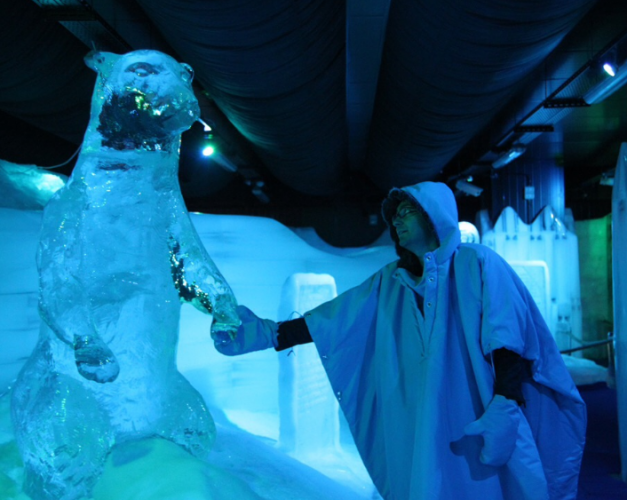أحد زوار متحف الثلج يرتدي لبس الاسكيمو ويلتقط صورة لنفسه